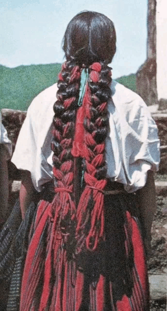 a woman wearing a white shirt and a red dress has a braided ponytail