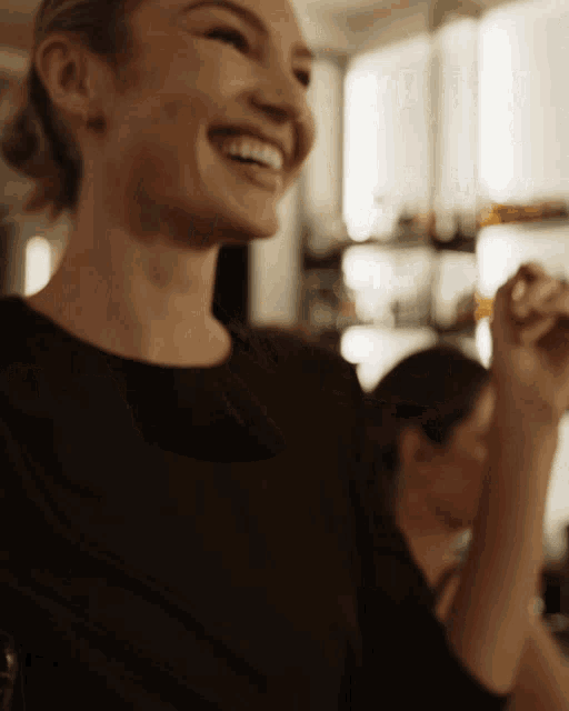 a woman in a black shirt is smiling and holding her arm up