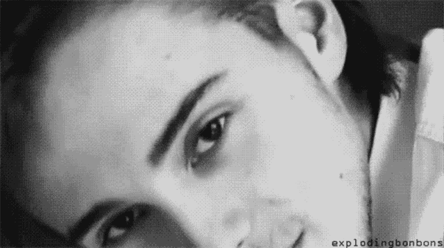 a close up of a man 's face in a black and white photo with his eyes closed .