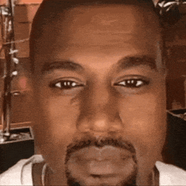 a close up of kanye west 's face with a beard and a white shirt .