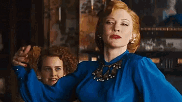 a woman in a blue dress is dancing with another woman