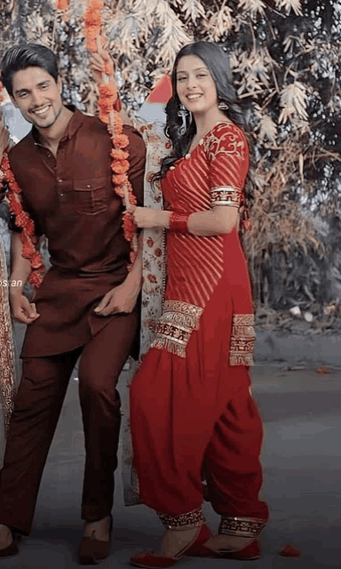 a man and a woman are posing for a picture while the woman is wearing a red dress .