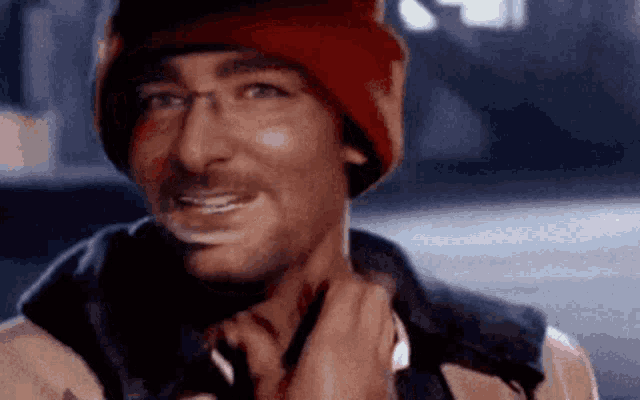 a man wearing a red hat and glasses is smiling while adjusting his tie .