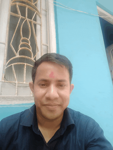 a man with a red circle on his forehead poses for a picture