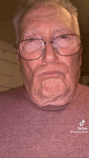 an elderly man wearing glasses has a tik tok written on his shirt