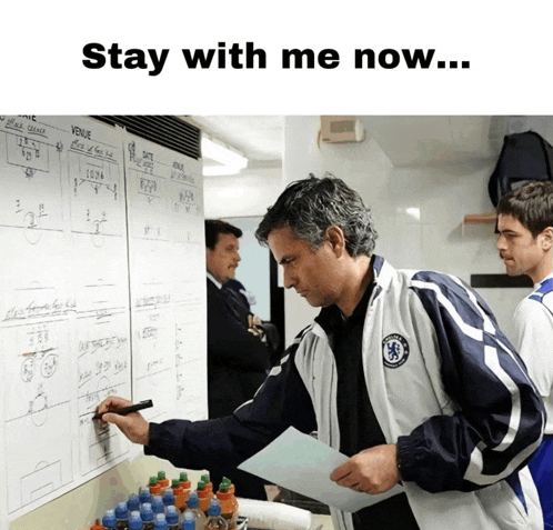 a man in a chelsea jacket is writing on a board