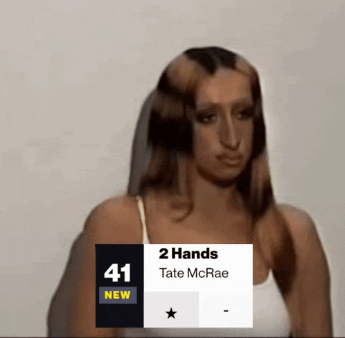 a woman 's face is behind a sign that says 2 hands tate mcrae