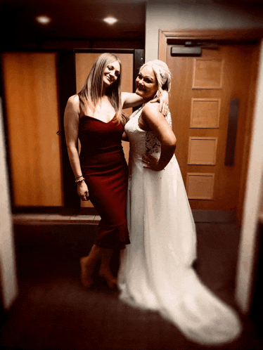 a woman in a red dress stands next to a woman in a wedding dress