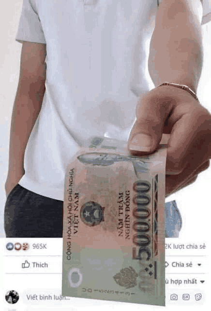 a man is holding a stack of money in his hand .