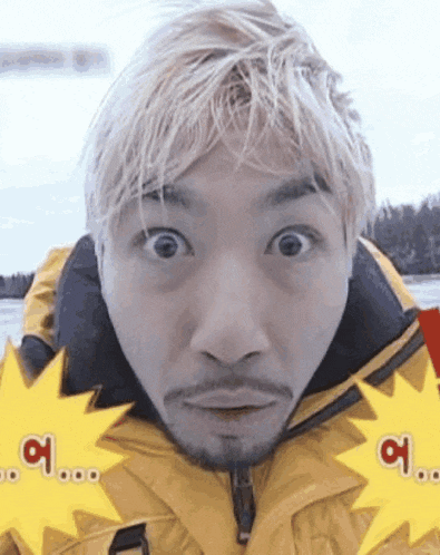 a man with blonde hair and a beard is making a funny face while wearing a yellow jacket .