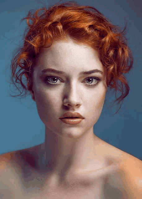 a woman with red hair and freckles looks at the camera