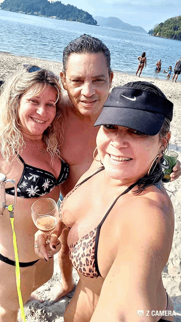 a man and two women are posing for a picture on a beach