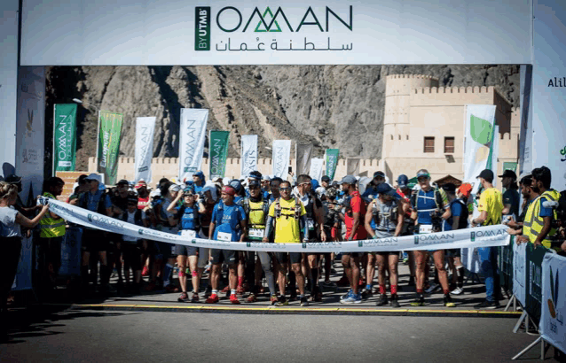 a group of people are gathered in front of a banner that says oman