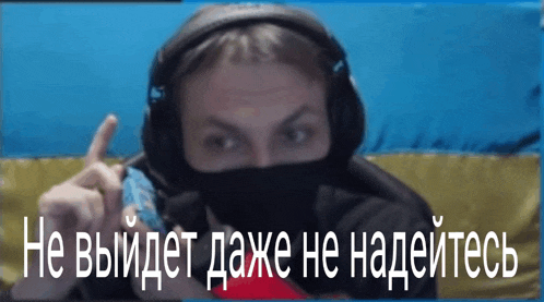 a man wearing headphones and a mask is giving a thumbs up in russian