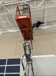 a man is standing on a scissor lift in a building