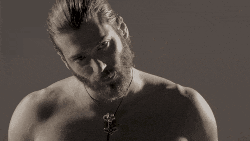 a shirtless man with a beard and a necklace with an anchor pendant