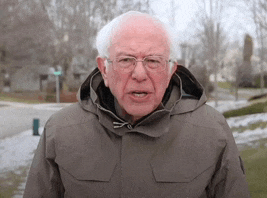 a man wearing glasses and a jacket with a hood is standing in the snow .