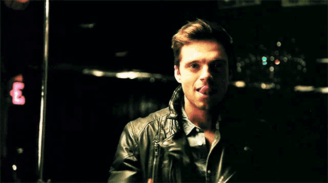 a man in a leather jacket is sticking out his tongue