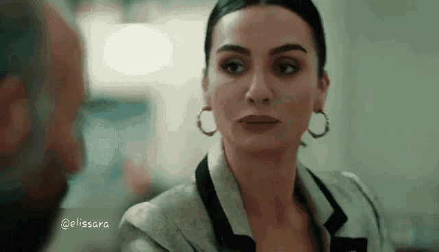 a woman wearing hoop earrings is looking at a man in a room .