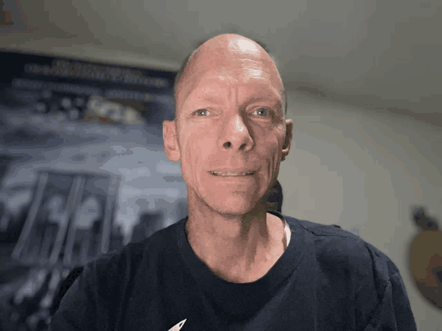 a bald man wearing a blue shirt stands in front of a sign that says 9/11