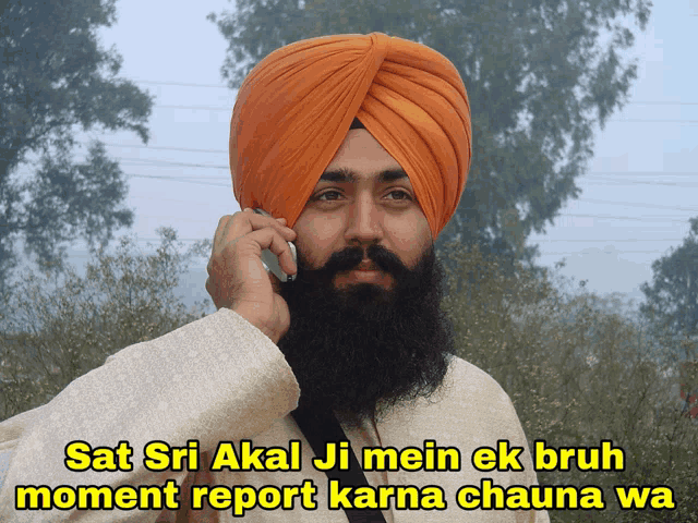 a man in an orange turban talking on a cell phone