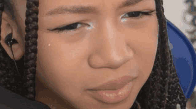 a close up of a girl 's face with braids and ear buds