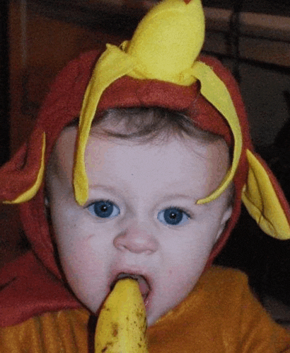 a baby wearing a red and yellow costume with a banana on his head