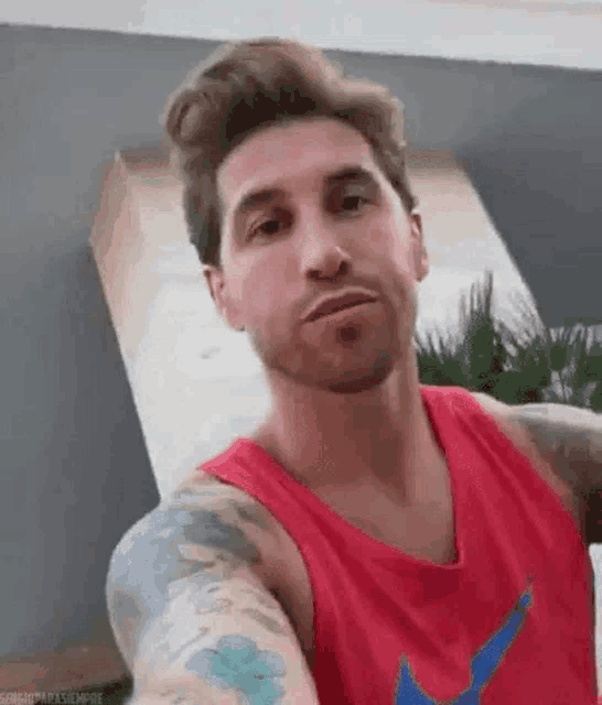 a man with tattoos on his arms and chest is taking a selfie .