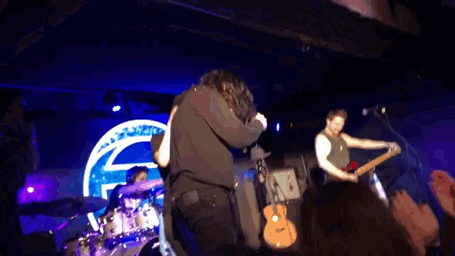 a man playing a guitar in front of a crowd with a sign that says ' e ' on it