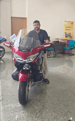 man standing next to a red honda motorcycle