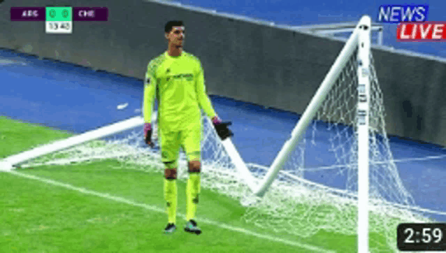 a soccer goalie stands in front of a broken goal net during a live broadcast