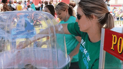 a woman wearing a green shirt that says burlington on it stands in front of a cotton candy machine