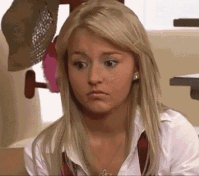 a blonde woman wearing a white shirt and a red tie is looking at the camera .