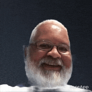 a bald man with glasses and a beard is smiling