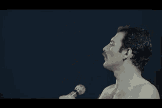 a shirtless man singing into a microphone with the word pressure written below him