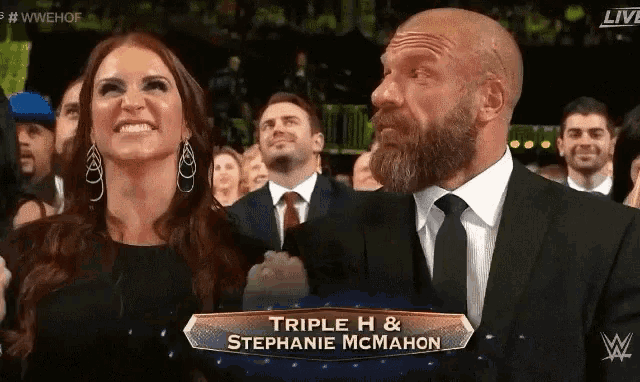 triple h and stephanie mcmahon are sitting in the audience at a wrestling event