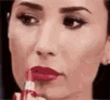 a woman is applying lipstick to her lips .