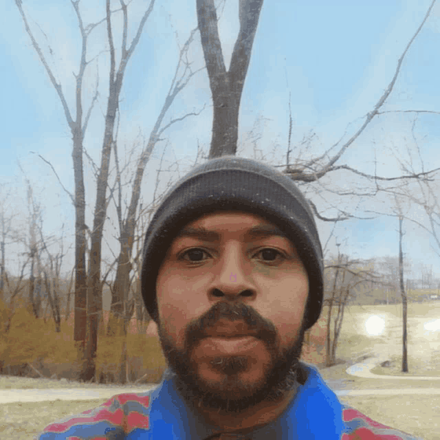 a man with a beard is wearing a beanie and a blue shirt