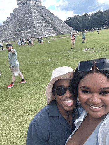 a man and woman posing for a picture in front of a pyramid