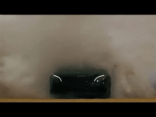 the front of a black car is covered in smoke and dust