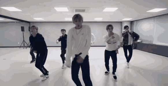 a group of young men are dancing together in a room .