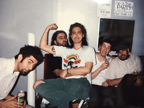 a group of men are posing for a picture with a sign that says end of tour party