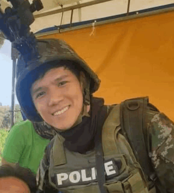 a soldier wearing a helmet and a vest is smiling for the camera .