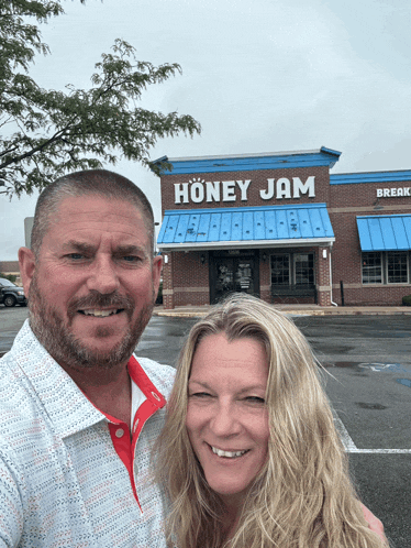 a man and a woman are posing in front of a honey jam restaurant