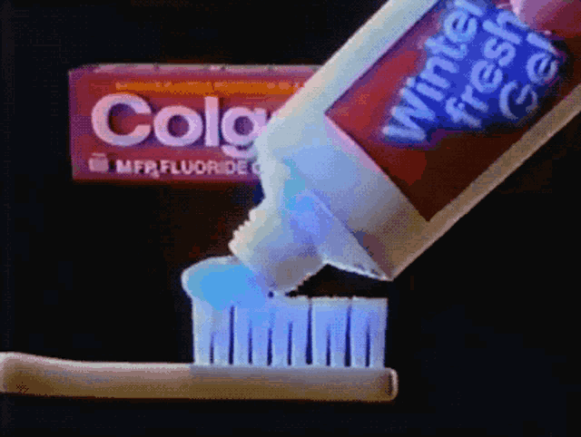 a tube of colgate toothpaste is being poured onto a toothbrush