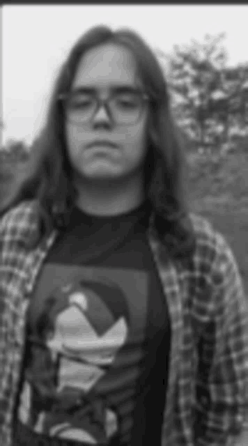 a black and white photo of a young man with long hair and glasses