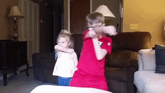 a boy and a girl are dancing in a living room and the boy is wearing a red shirt with the letter y on it