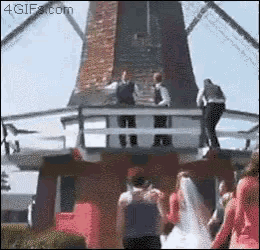 a group of people are standing in front of a windmill and the website 4gifs.com is in the corner