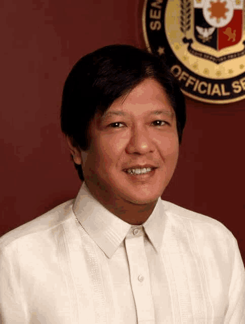 a man in a white shirt is smiling in front of a seal that says official service