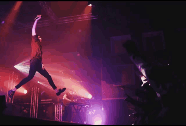 a man is jumping in the air with a microphone in his hand